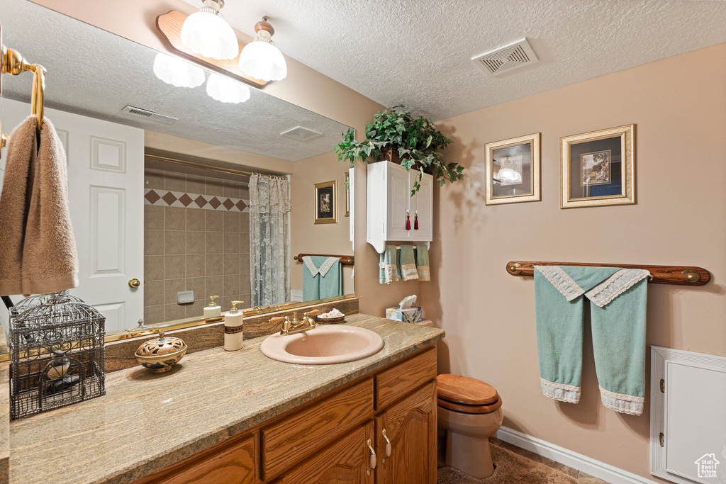 Bathroom with toilet, vanity, a textured ceiling, and curtained shower
