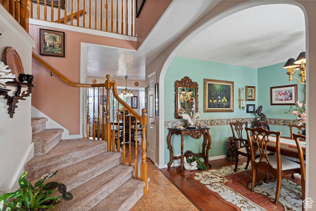 Foyer entrance featuring a chandelier, stairway, arched walkways, a textured ceiling, and wood finished floors