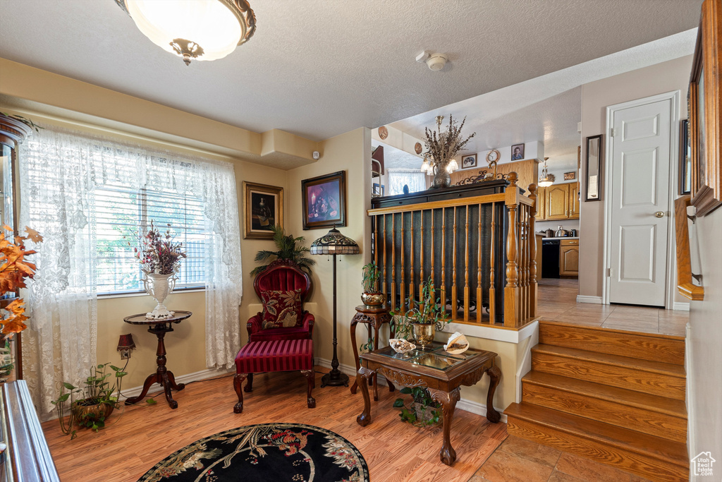 Living area featuring light wood finished floors, baseboards, a textured ceiling, and stairs
