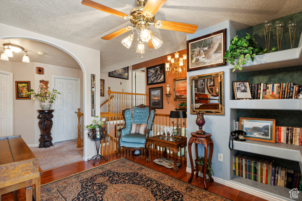 Living area with wood finished floors, ceiling fan, arched walkways, a textured ceiling, and stairway