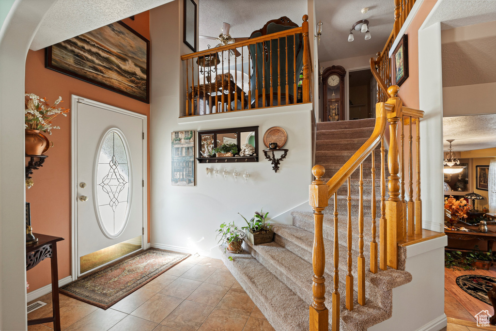 Entryway with stairs, arched walkways, tile patterned flooring, and baseboards