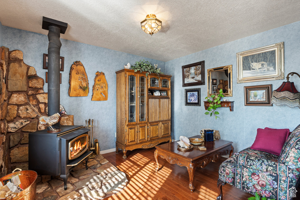 Living room featuring a wood stove, hardwood / wood-style flooring, and a textured ceiling