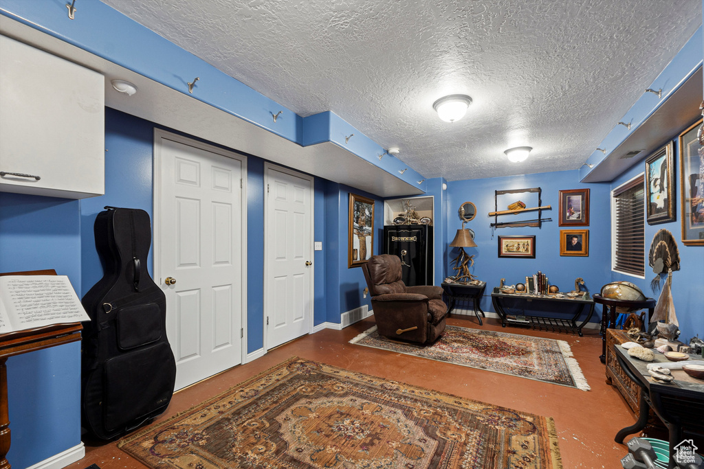 Living room with a textured ceiling, finished concrete flooring, and baseboards