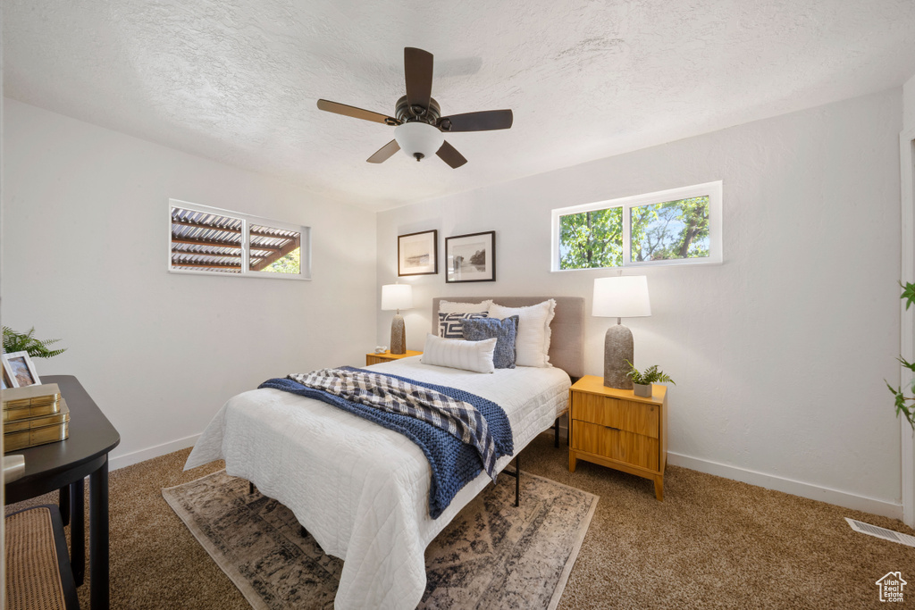 Bedroom with light colored carpet, baseboards, ceiling fan, and a textured ceiling
