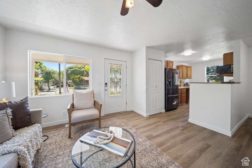 Living area with baseboards, light wood finished floors, and a textured ceiling