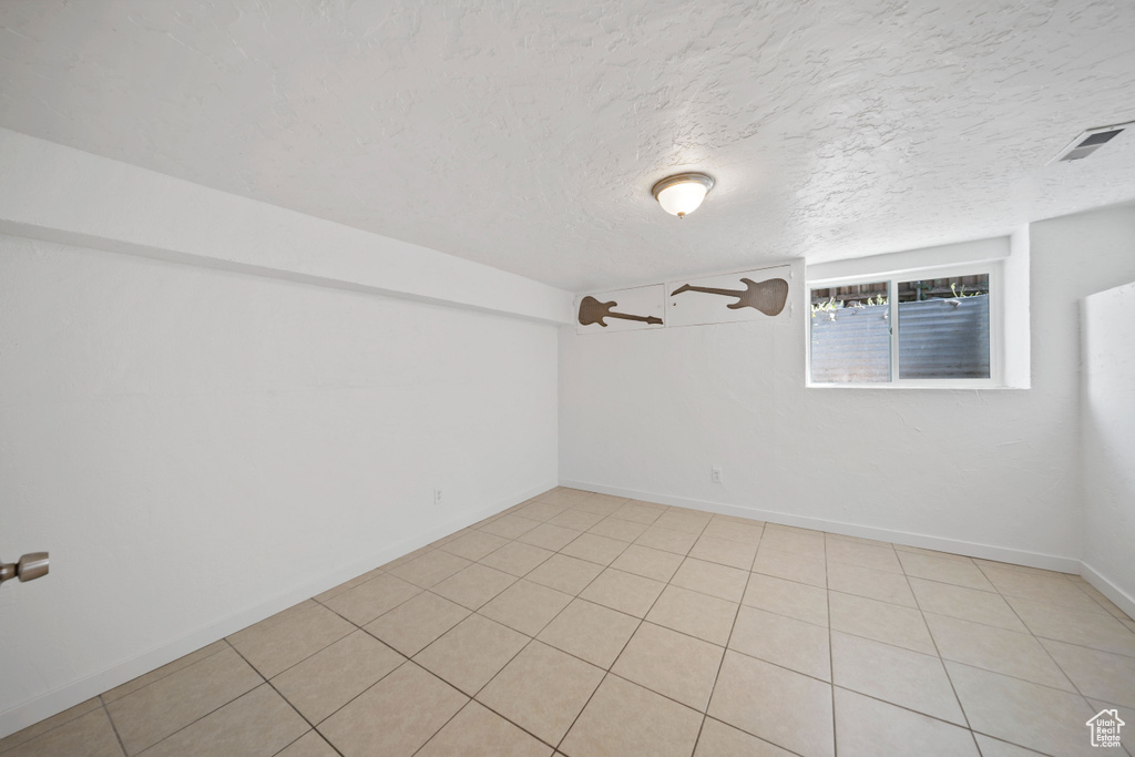 Empty room with a textured ceiling and baseboards