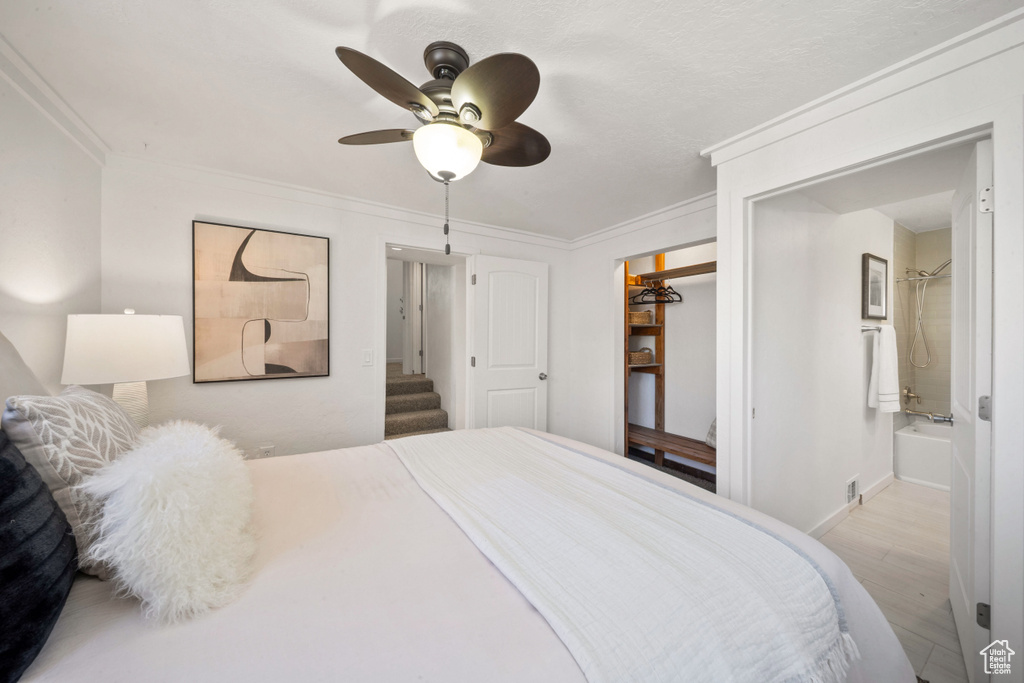 Bedroom featuring wood finished floors, crown molding, ceiling fan, baseboards, and ensuite bath