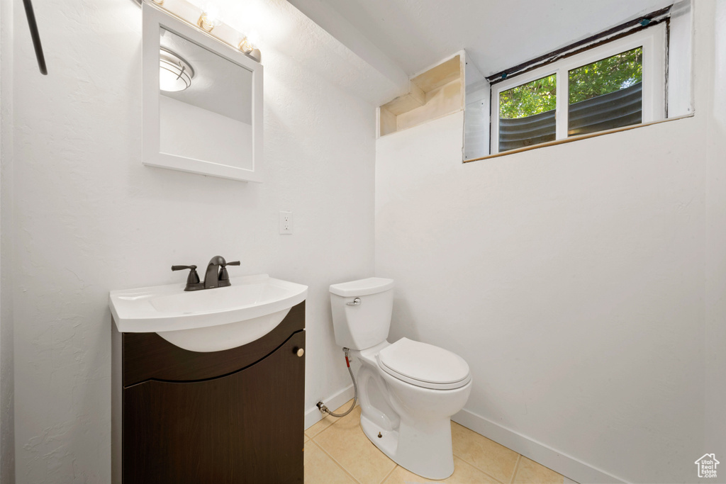 Half bath with vanity, toilet, tile patterned flooring, and baseboards