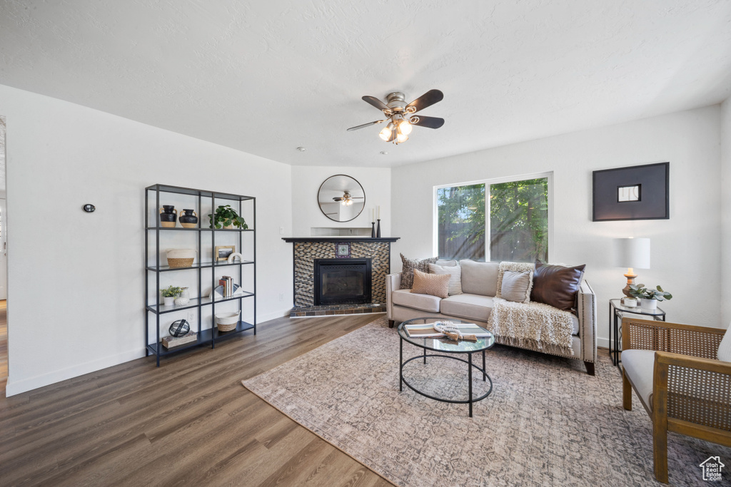 Living area with wood finished floors, a ceiling fan, a fireplace, and baseboards