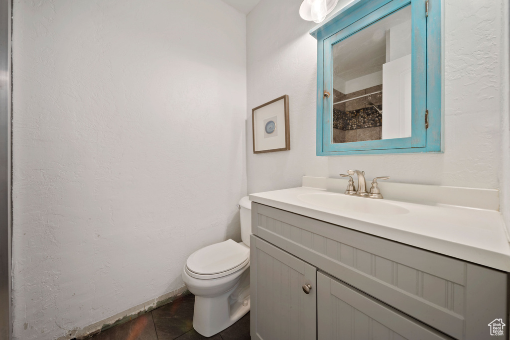 Full bathroom with toilet, vanity, tile patterned floors, and a shower