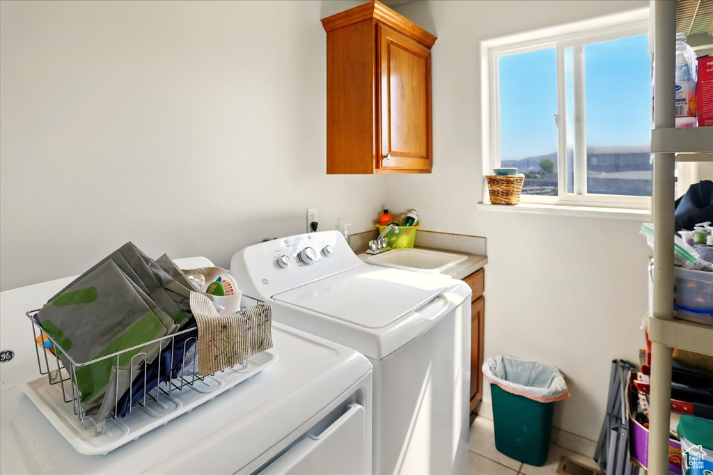 Laundry area featuring washer and clothes dryer, cabinet space, and light tile patterned flooring