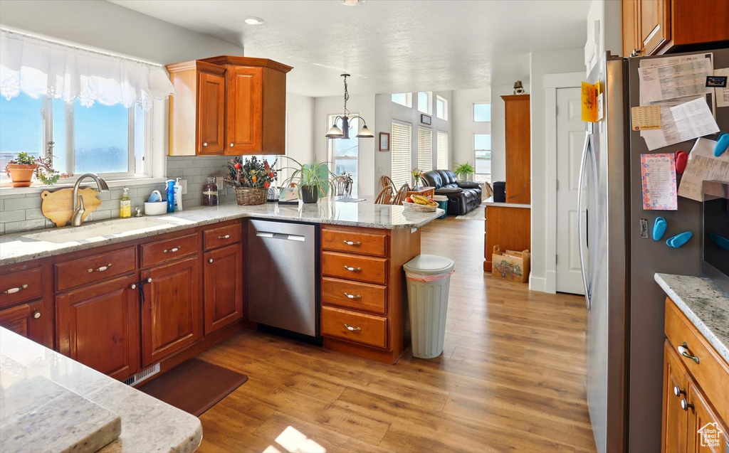 Kitchen with stainless steel appliances, a sink, a peninsula, and light wood-type flooring