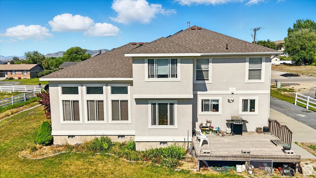 Rear view of house with roof with shingles, crawl space, a deck with mountain view, and stucco siding