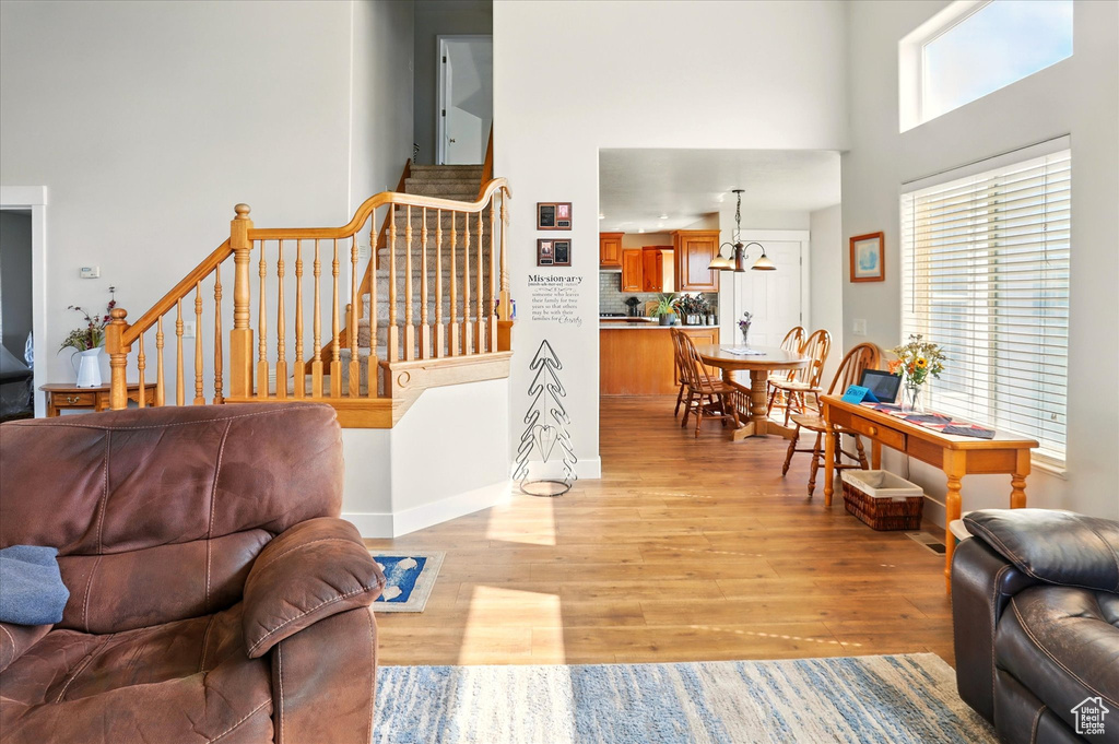 Living room featuring a high ceiling, light wood-type flooring, stairs, and baseboards