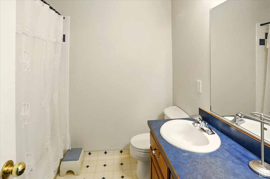 Full bathroom featuring toilet, vanity, curtained shower, and baseboards