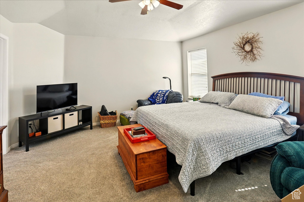 Carpeted bedroom with a ceiling fan and baseboards