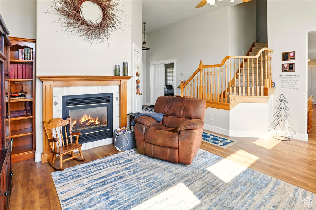 Living room featuring stairway, wood finished floors, a fireplace, ceiling fan, and baseboards