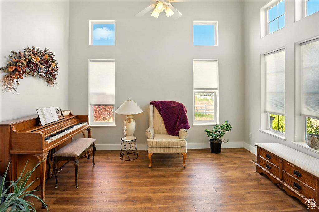 Living area with a high ceiling, ceiling fan, wood finished floors, and baseboards