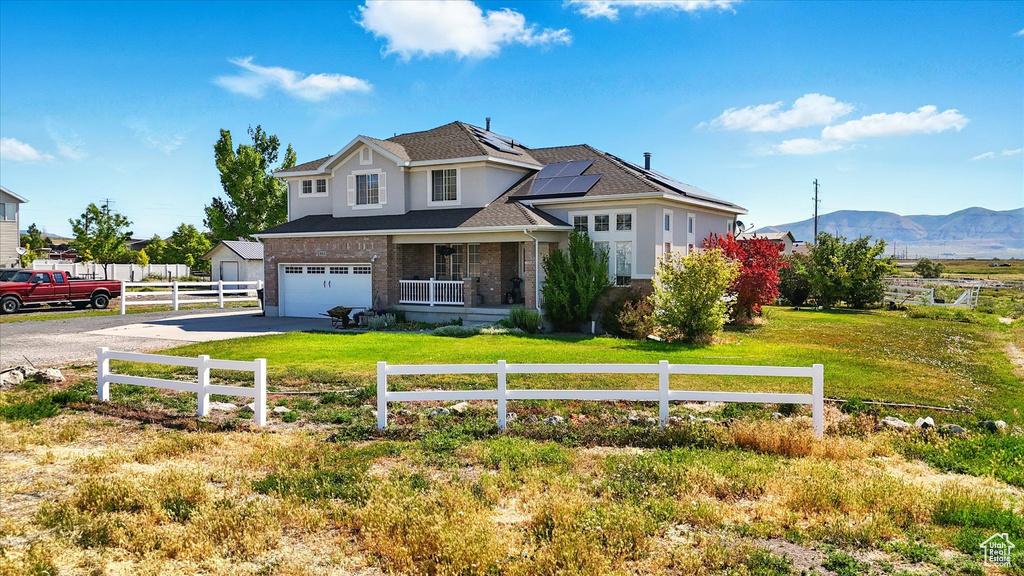 Traditional-style home with concrete driveway, roof mounted solar panels, a mountain view, a garage, and brick siding