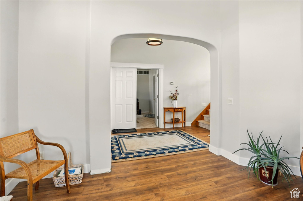 Hallway featuring arched walkways, wood finished floors, and stairs