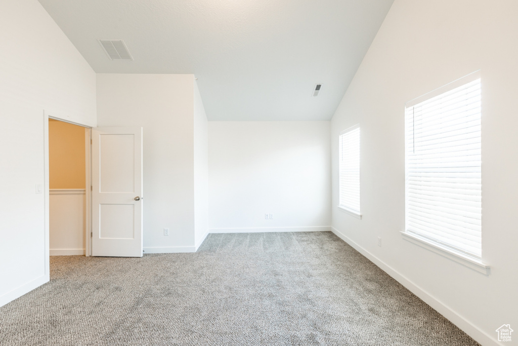 Empty room featuring light carpet and high vaulted ceiling