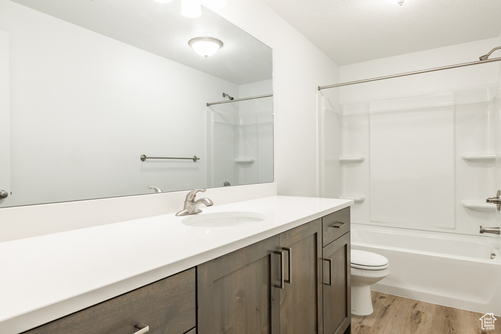 Full bathroom with hardwood / wood-style flooring, shower / tub combination, vanity, and toilet