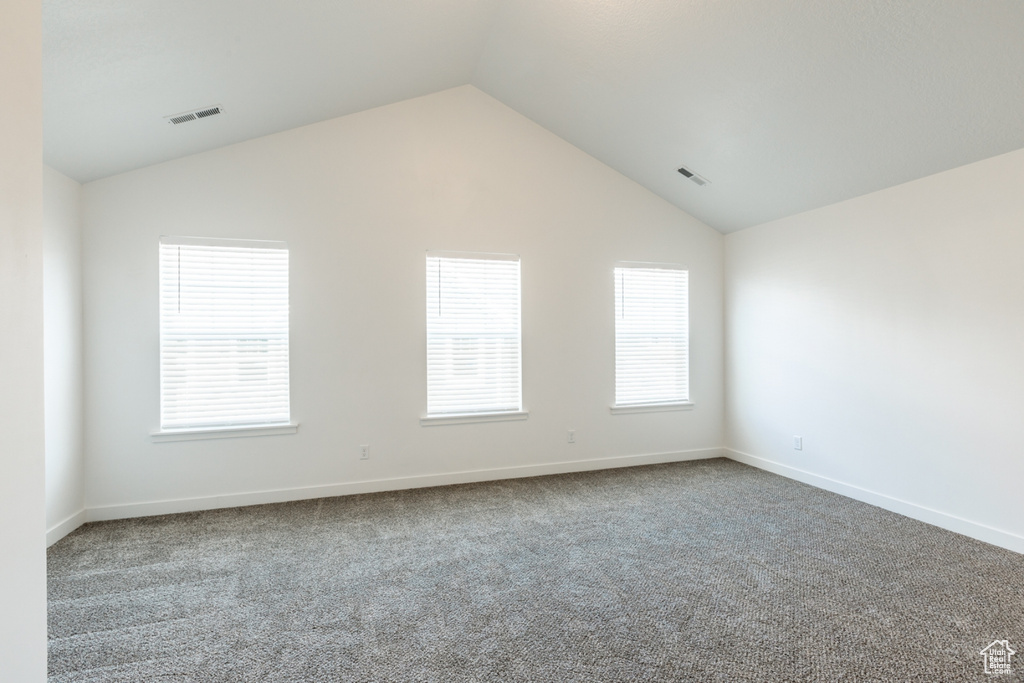 Empty room with carpet floors and vaulted ceiling