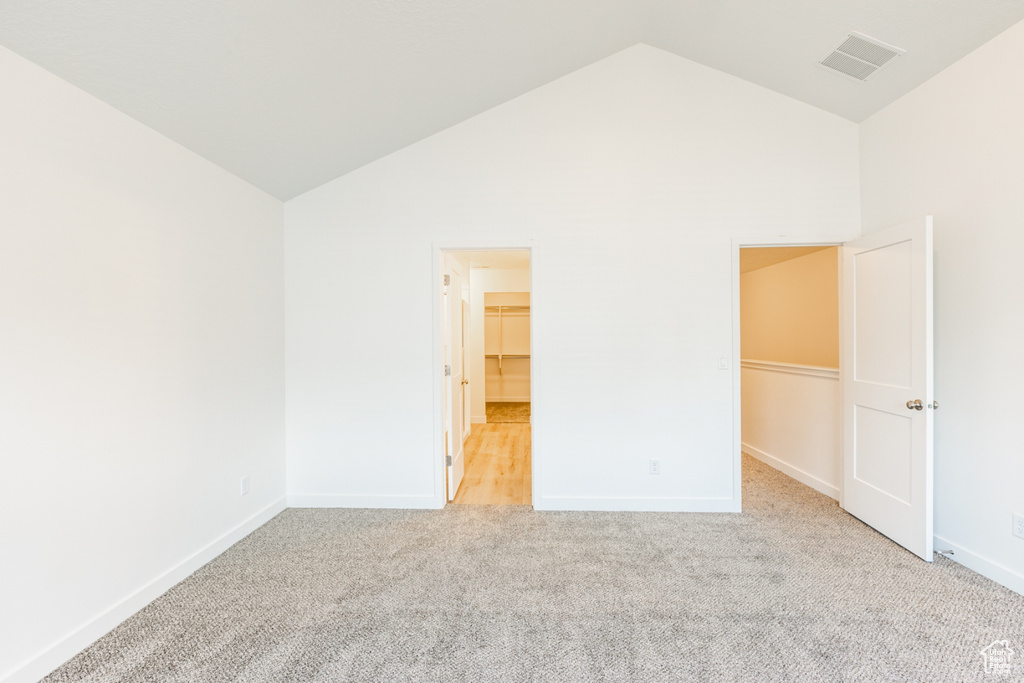 Empty room with light colored carpet and high vaulted ceiling