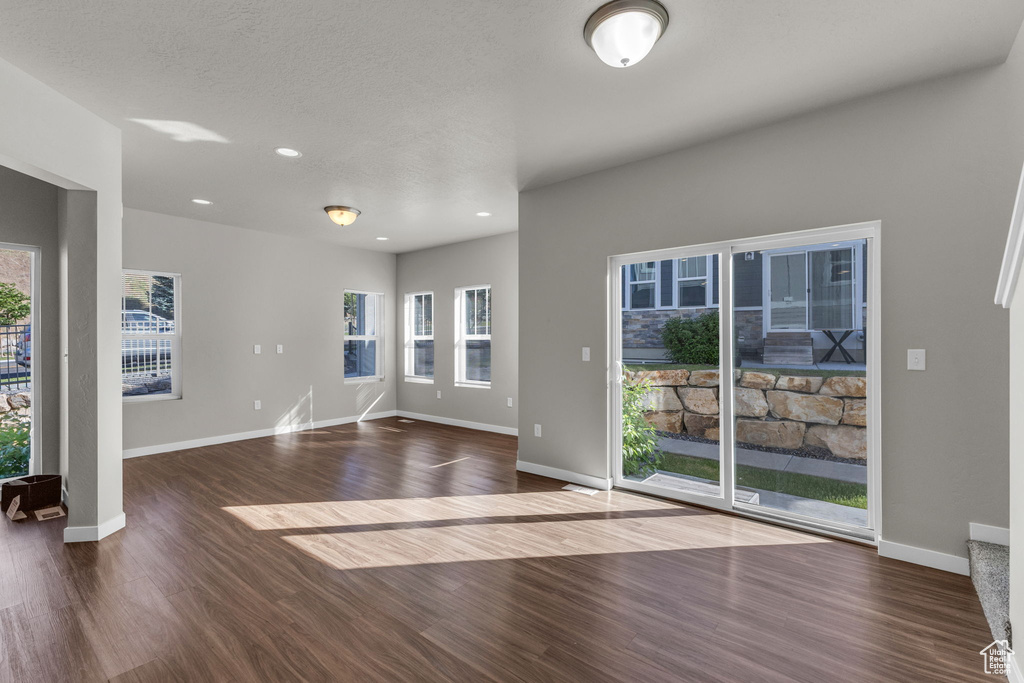 Unfurnished living room featuring dark wood finished floors, baseboards, and recessed lighting