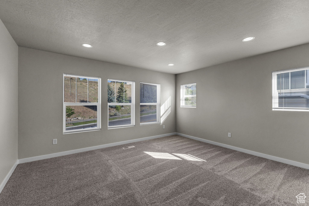 Unfurnished room featuring a textured ceiling, carpet floors, recessed lighting, and baseboards