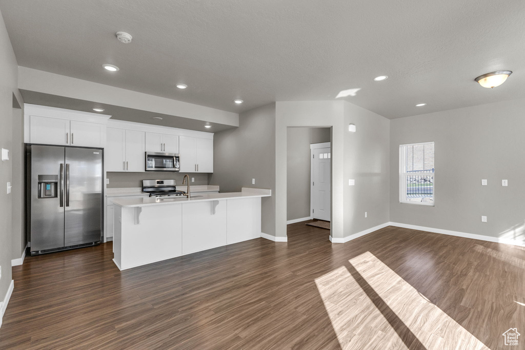 Kitchen featuring appliances with stainless steel finishes, baseboards, light countertops, dark wood finished floors, and recessed lighting