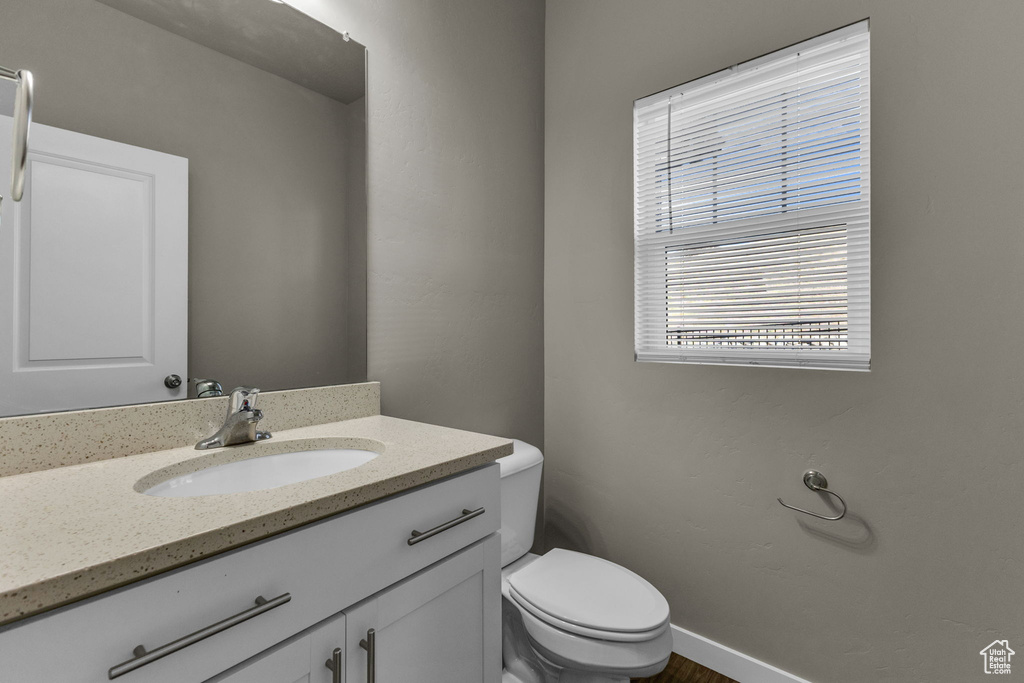 Half bath with toilet, vanity, and baseboards