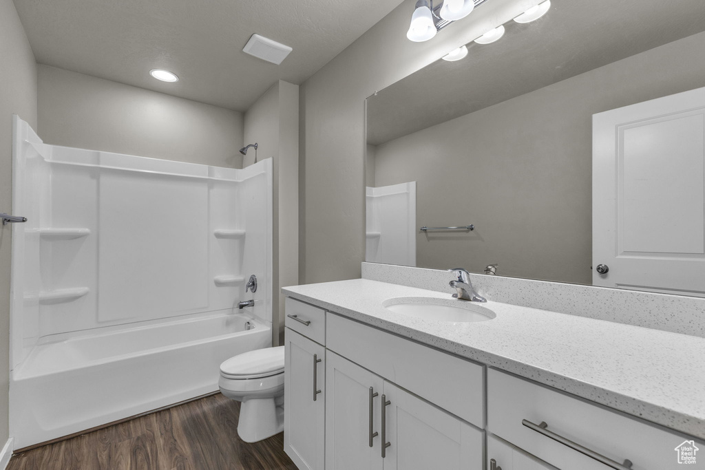 Full bath featuring wood finished floors, vanity, toilet,  shower combination, and recessed lighting