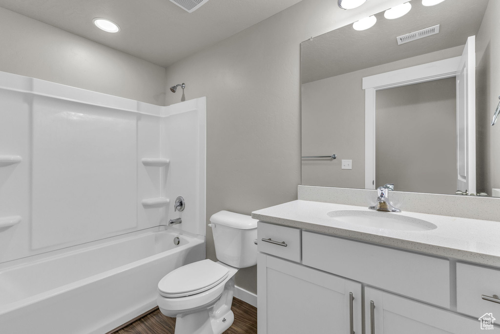 Bathroom with wood finished floors, vanity, toilet, shower / tub combination, and baseboards