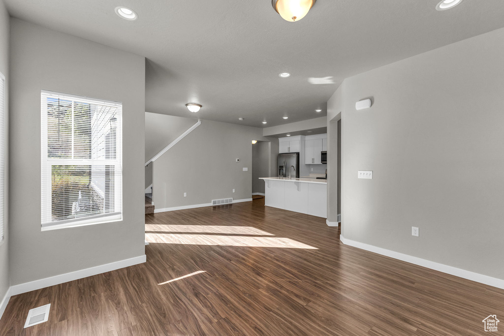 Unfurnished living room with baseboards, dark wood-type flooring, and recessed lighting