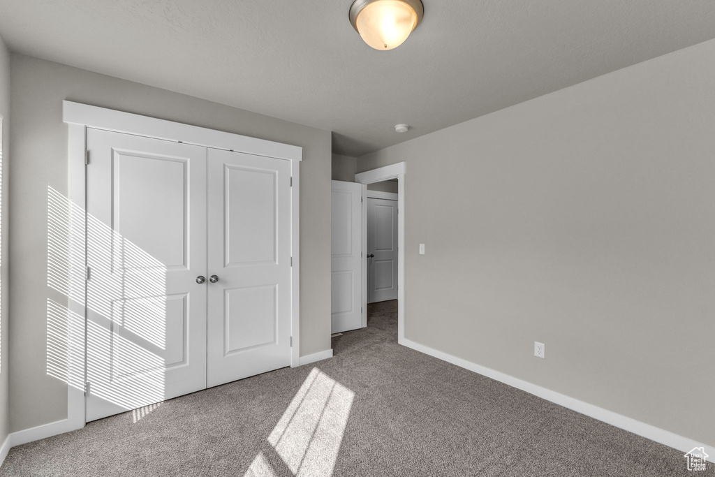 Unfurnished bedroom with carpet floors, baseboards, and a closet