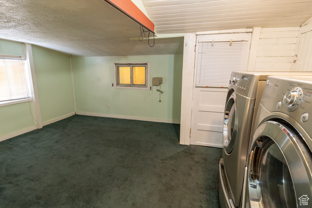 Laundry area featuring separate washer and dryer, dark carpet, baseboards, and a textured ceiling