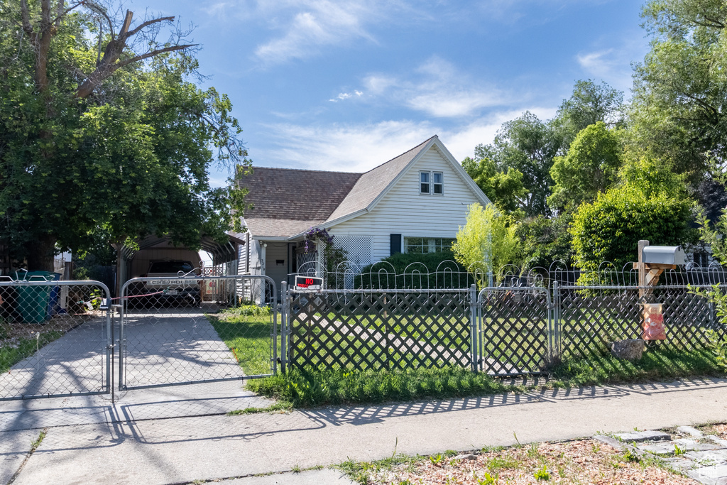 View of front of house with a carport, concrete driveway, a gate, and a shingled roof