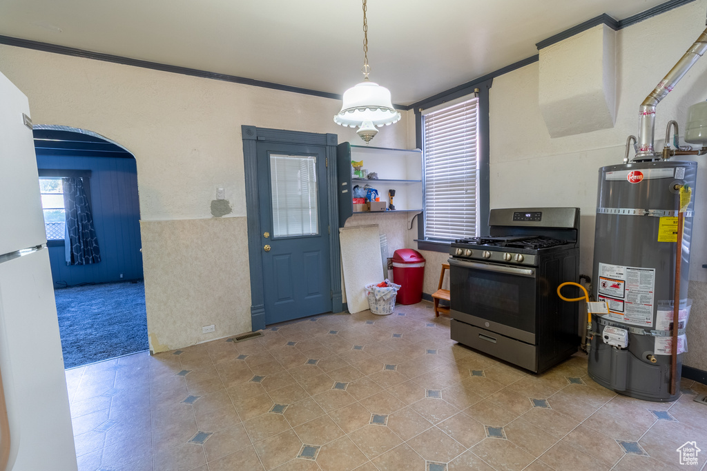 Kitchen with stainless steel range with gas cooktop, secured water heater, arched walkways, tile patterned flooring, and freestanding refrigerator