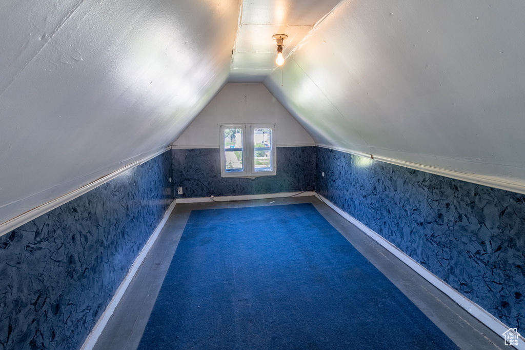 Additional living space featuring vaulted ceiling, wallpapered walls, and carpet