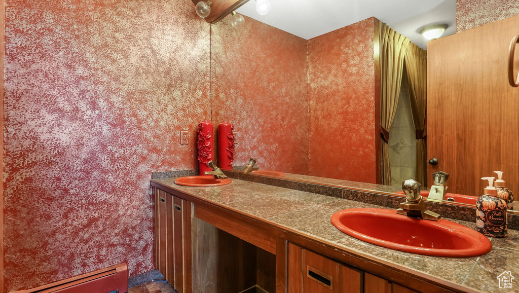 Full bath with a baseboard heating unit and double vanity