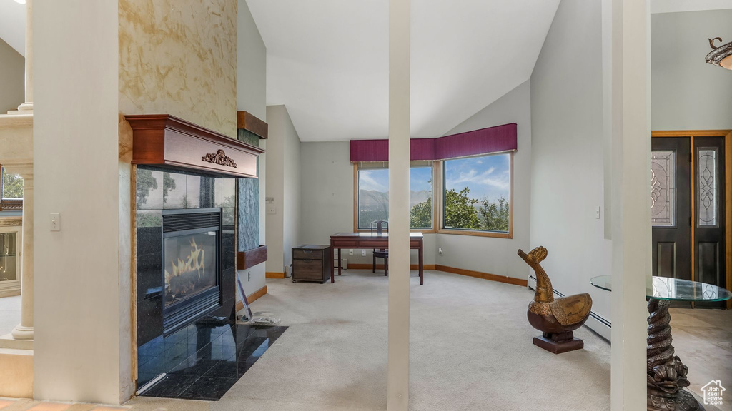 Carpeted living area featuring vaulted ceiling, a tile fireplace, and baseboards