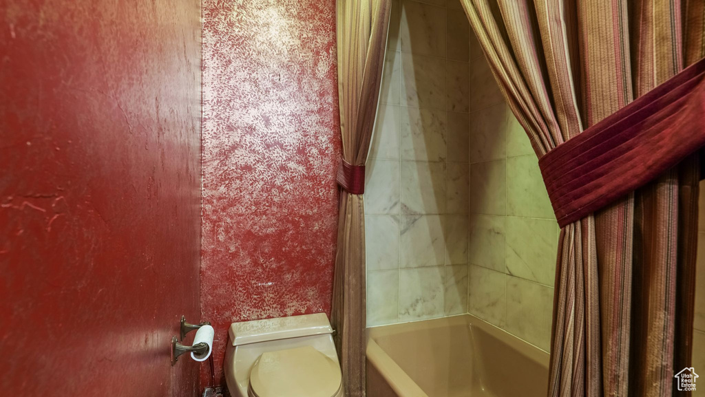 Full bathroom featuring toilet and shower / tub combo with curtain