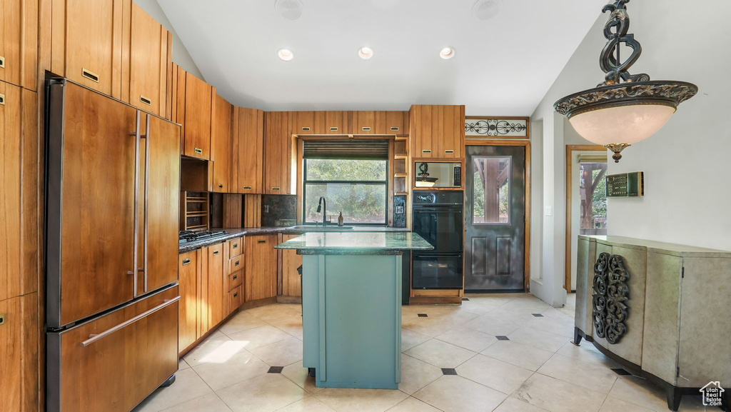 Kitchen featuring high quality fridge, vaulted ceiling, a sink, dark countertops, and a kitchen island