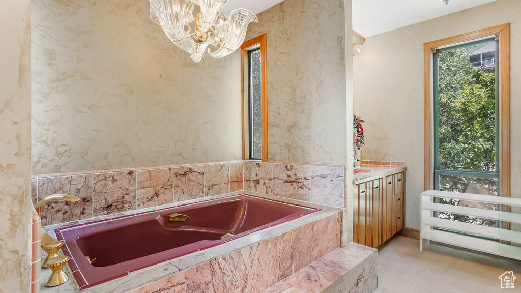 Full bathroom featuring a bath, a chandelier, and vanity