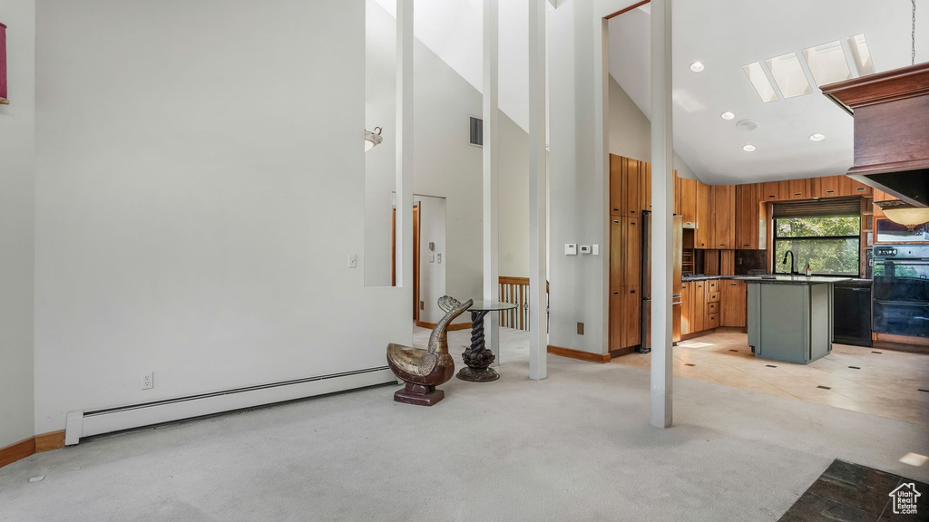 Unfurnished living room featuring a baseboard heating unit, light carpet, high vaulted ceiling, baseboards, and recessed lighting