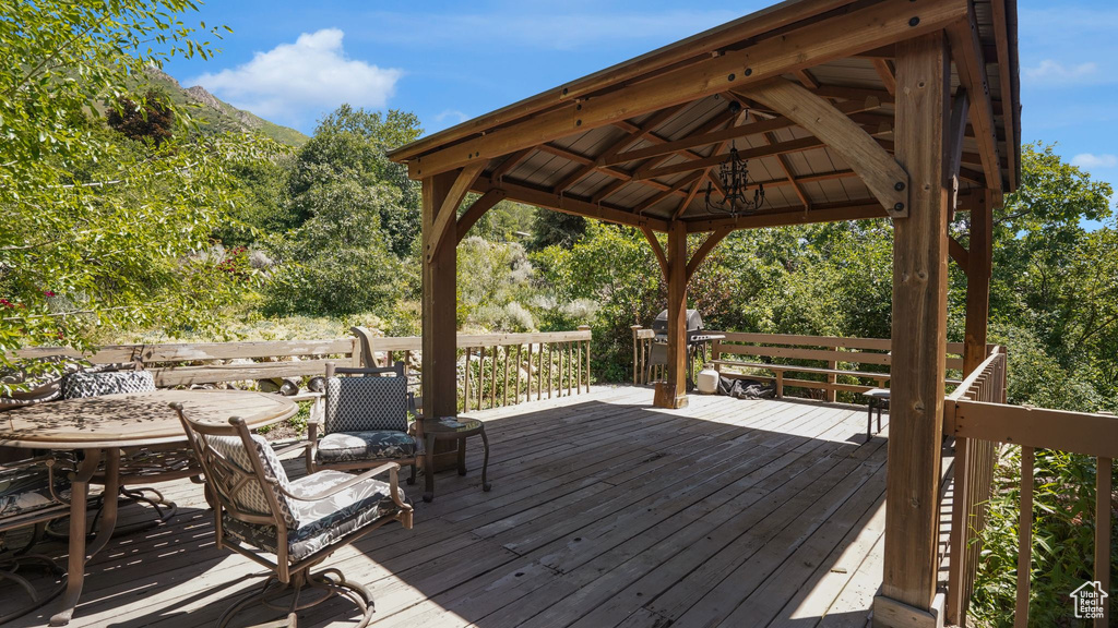 Deck with outdoor dining space, a gazebo, and grilling area