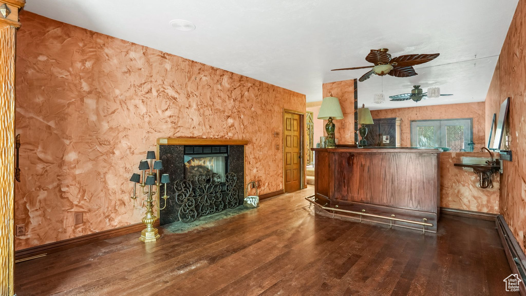 Living area with baseboard heating, wood finished floors, ceiling fan, a multi sided fireplace, and baseboards
