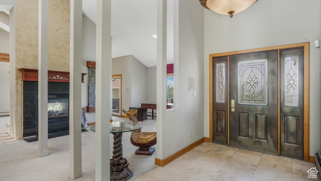Foyer with high vaulted ceiling, a baseboard heating unit, a fireplace, and baseboards