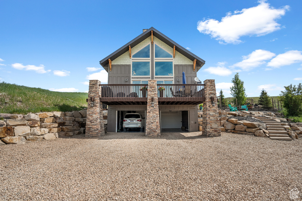 Rear view of house with a carport, gravel driveway, and a wooden deck